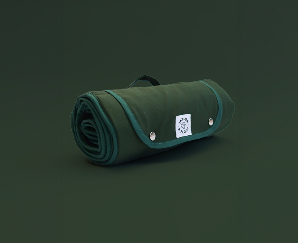 Dark green settle mat. Solid colour mat rolled up on a green background.